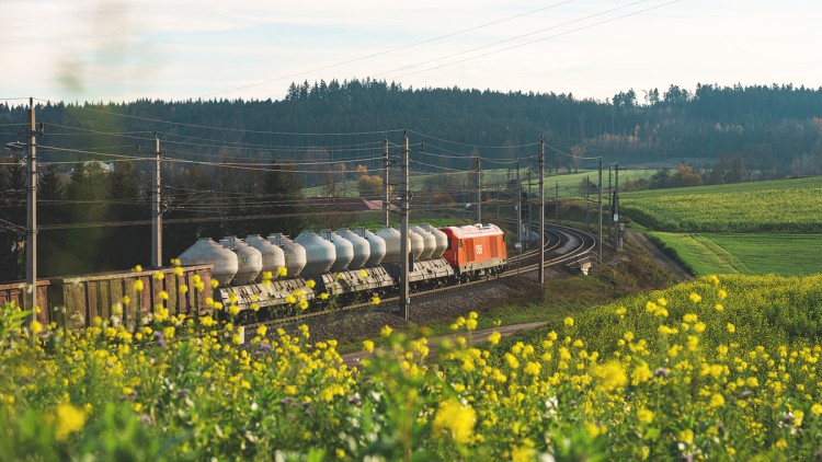 Ein Zug der ÖBB Rail Cargo Group transportiert durch eine idyllische Landschaft.