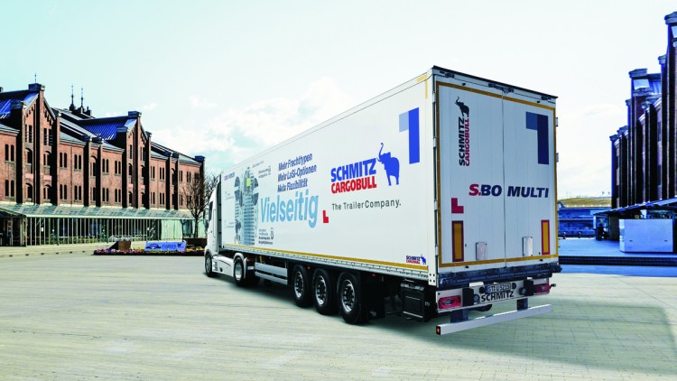 Seitliche Ansicht von hinten des neuen S.BO Multi von Schmitz Cargobull. Der dreiachsige Kofferauflieger steht in einer urbanen Umgebung, eine Sattelzugmaschine ist angehängt