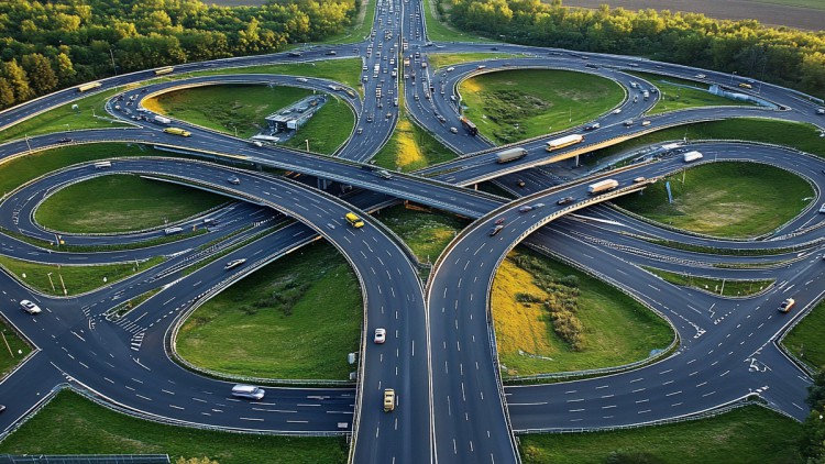 Luftaufnahme auf ein Autobahnkreuz im Sonnenaufgang mit vier Auffahrten und einem Zufahrtsring außenrum