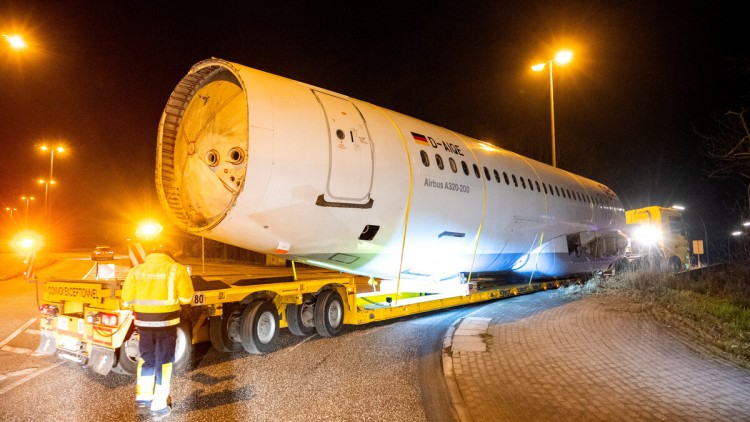 Ein mit einem Airbus-Flugzeugrumpf beladener Schwertransport fährt am 24. Januar 2023 zum Zentrum für Angewandte Luftfahrtforschung (ZAL). Das Teil des ehemaligen Flugzeugs wurde in der Nacht von der Lufthansa Technik zum ZAL für Forschungszwecke gebracht