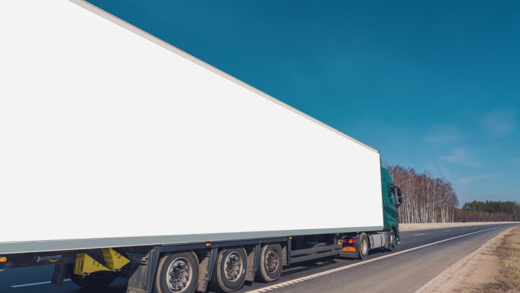 Ein langer Lkw mit einem weißen Trailer fährt auf einer Straße