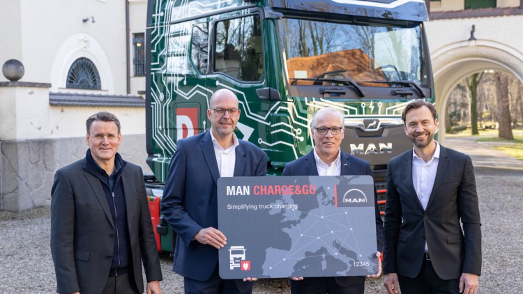 Vor dem MAN eTGX mit Duvenbeck-Unternehmensfarben und Logo stehen mit einer großen grauen Karte, auf der "MAN Charge&Go" zu lesen ist: Alexander Vlaskamp, Vorstandsvorsitzender MAN Truck & Bus, Bernd Reining, Senior Director Procurement, Duvenbeck, Friedr