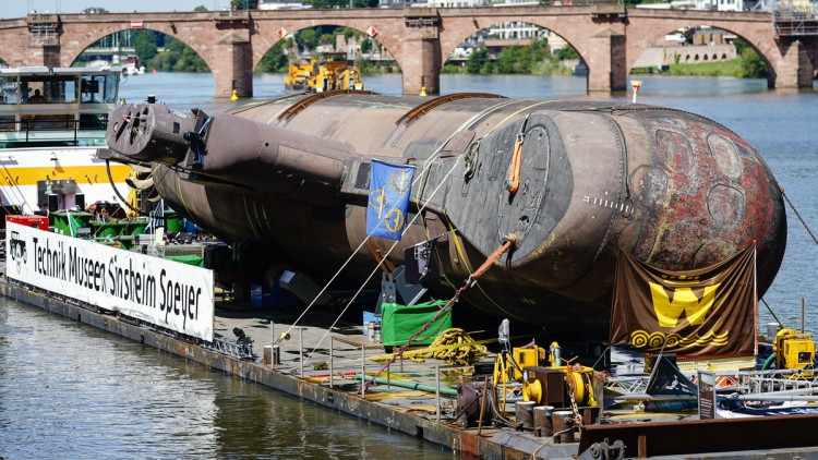 Das U-Boot U17 fährt auf einem Transportschiff vor der Alten Brücke bei Heidelberg in eine Schleuse