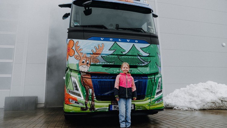 Die Gewinnerin Anja steht vor der Volvo-FH-Aero-Sattelzugmaschine, die mit ihrem Entwurf beklebt wurde  