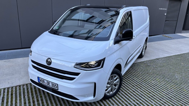 Seitliche Frontansicht des neuen Transporters. Der in weiß lackierte Kastenwagen steht vor einer modernen Lagerhalle