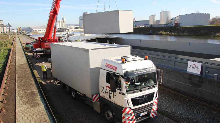 Kombiverkehr: Fertiggarage wird mit einem Kran von Spezial-Lkw auf Binnenschiff geladen