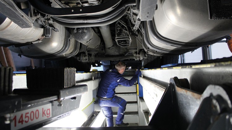 Kfz-Mechaniker prüft Fahrzeug von unten