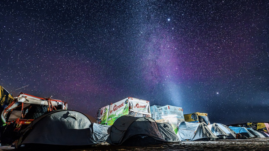 Zelte und Lkw vor einem sternübersäten Nachthimmel