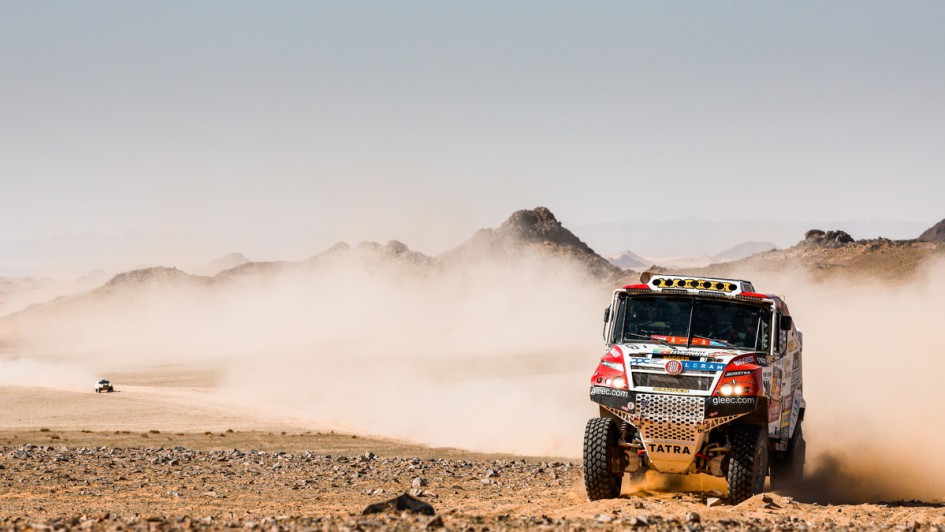 Truck fährt durch STaubwüste, im Hintergrund ein weiteres Auto der Rallye