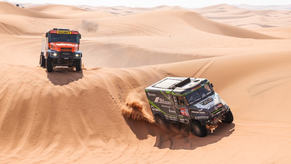 Zwei Trucks fahren hintereinander durch die Dünen der Wüste Saudi-Arabiens