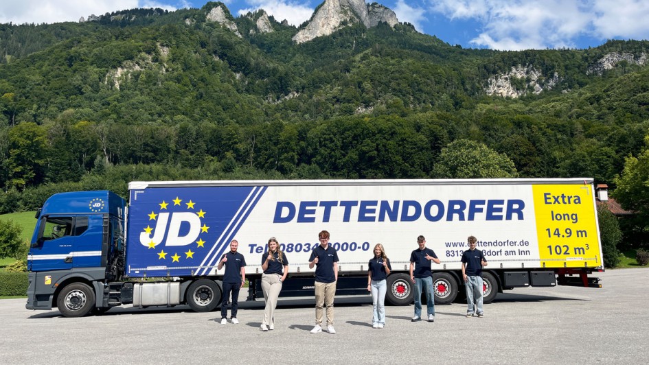 Sechs der sieben neuen Azubis von Dettendorfer vor einem Dettendorfer-Lkw vor einem Berg