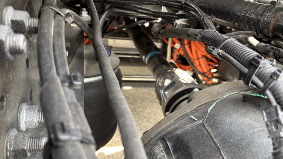 Detailaufnahme des Fahrgestells des Nova F-L von Rygg mit Kardanwelle, Leitungen, Achskomponenten und orange markierten Hochvoltkabeln.