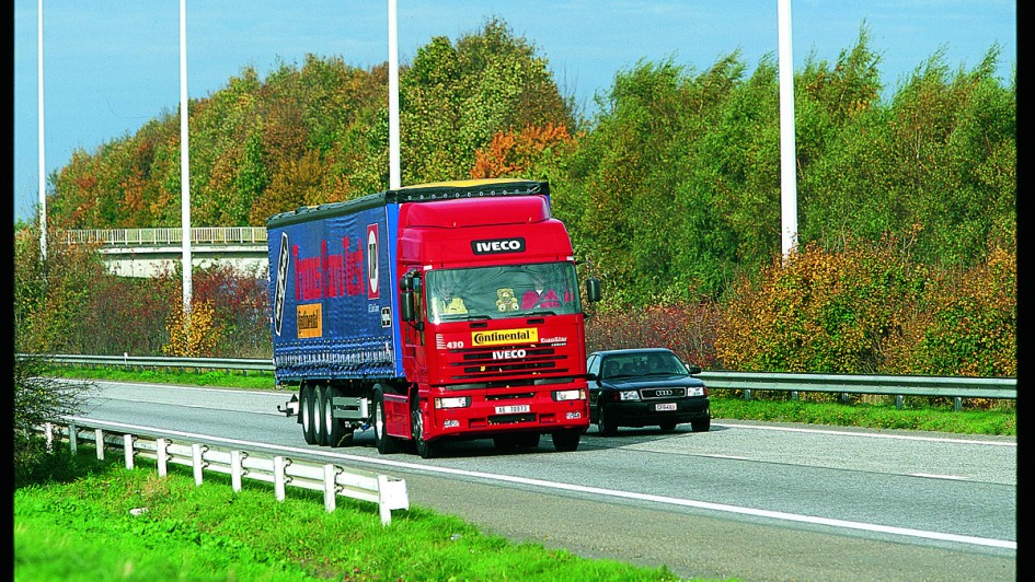 Ein in rot lackierter Iveco EuroStar mit 440 PS fährt auf der Autobahn. Das Fahrzeug ist mit einem blauen Sattelauflieger kombiniert 
