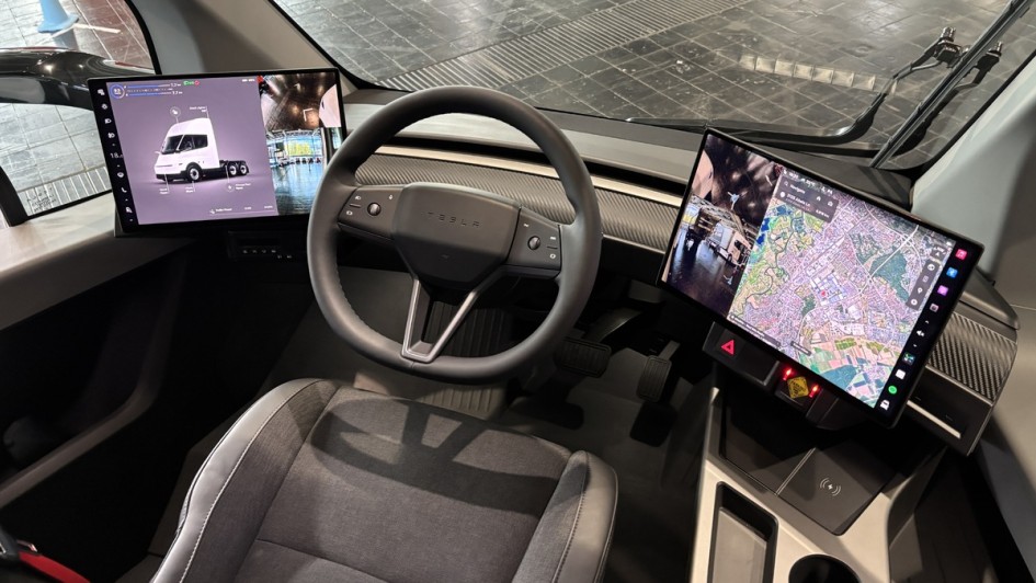 Blick auf das Cockpit des Tesla Semi mit der zentral platzierten Sitzposition. Man erkennt die beiden großen Bildschirme rechts und links neben dem Dreispeichenlenkrad